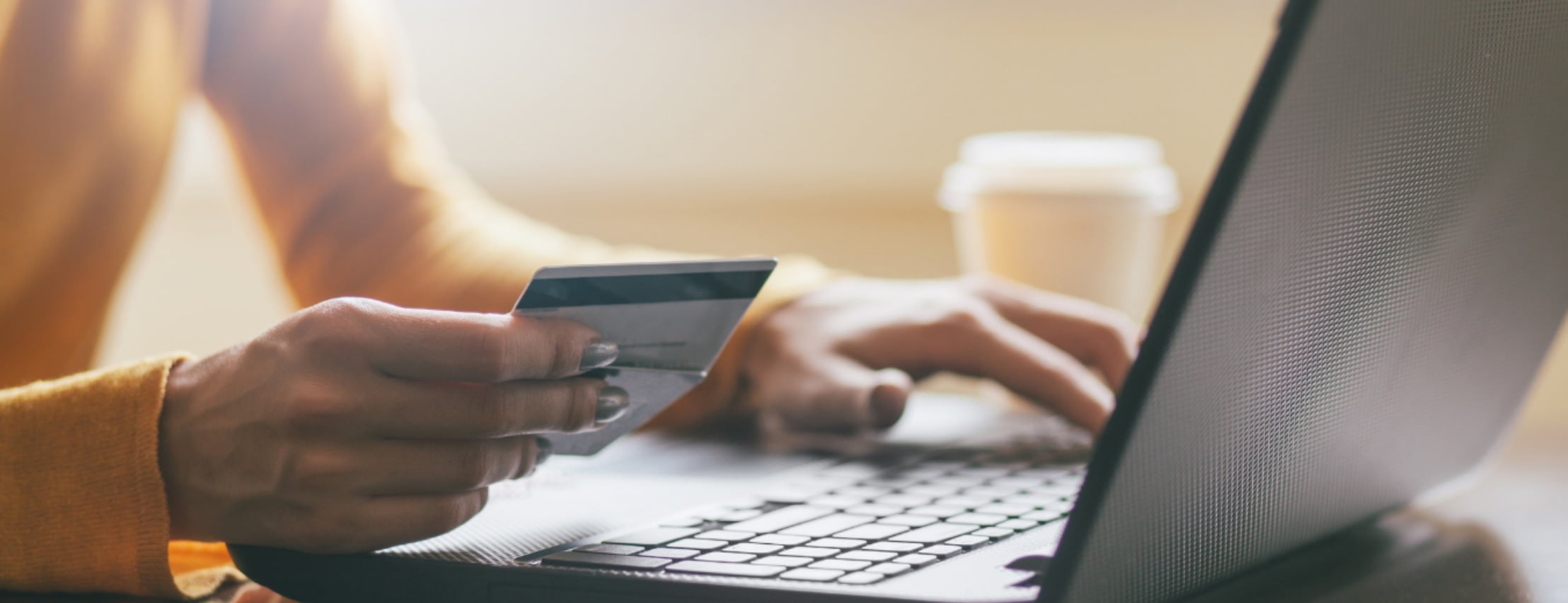 Hands typing on a keyboard while holding a credit card