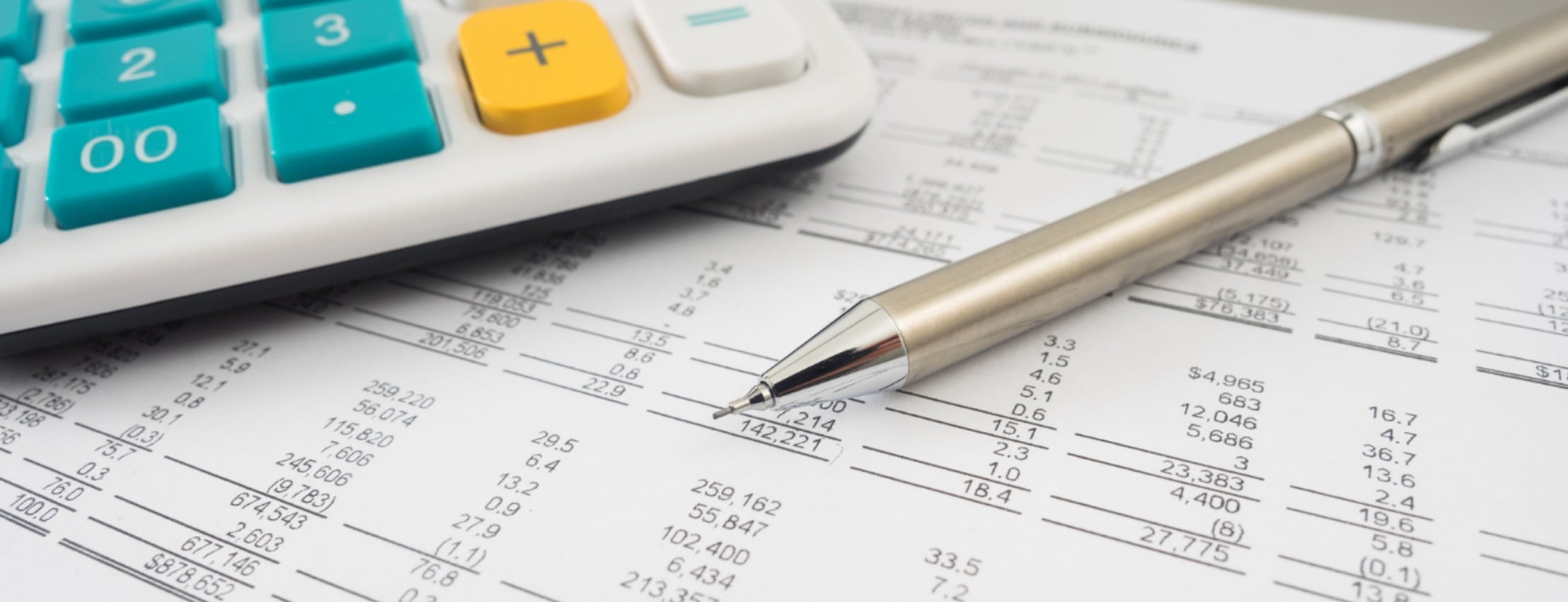 A calculator and mechanical pencil appear next to a small business balance sheet